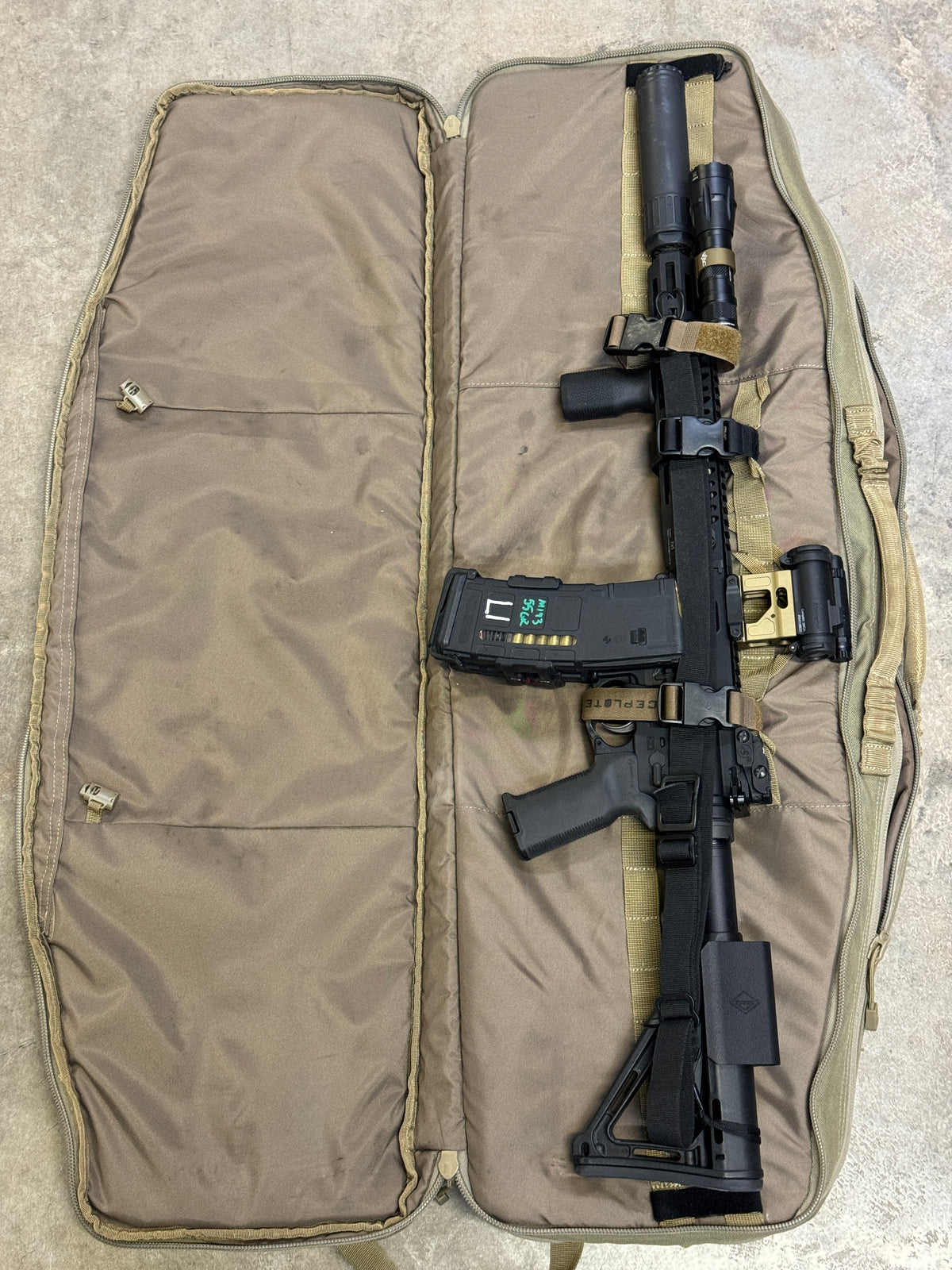 Ranger green MOLLE Velcro straps fastened around a rifle in a soft case, showing secure lashing and one-handed quick-release access.